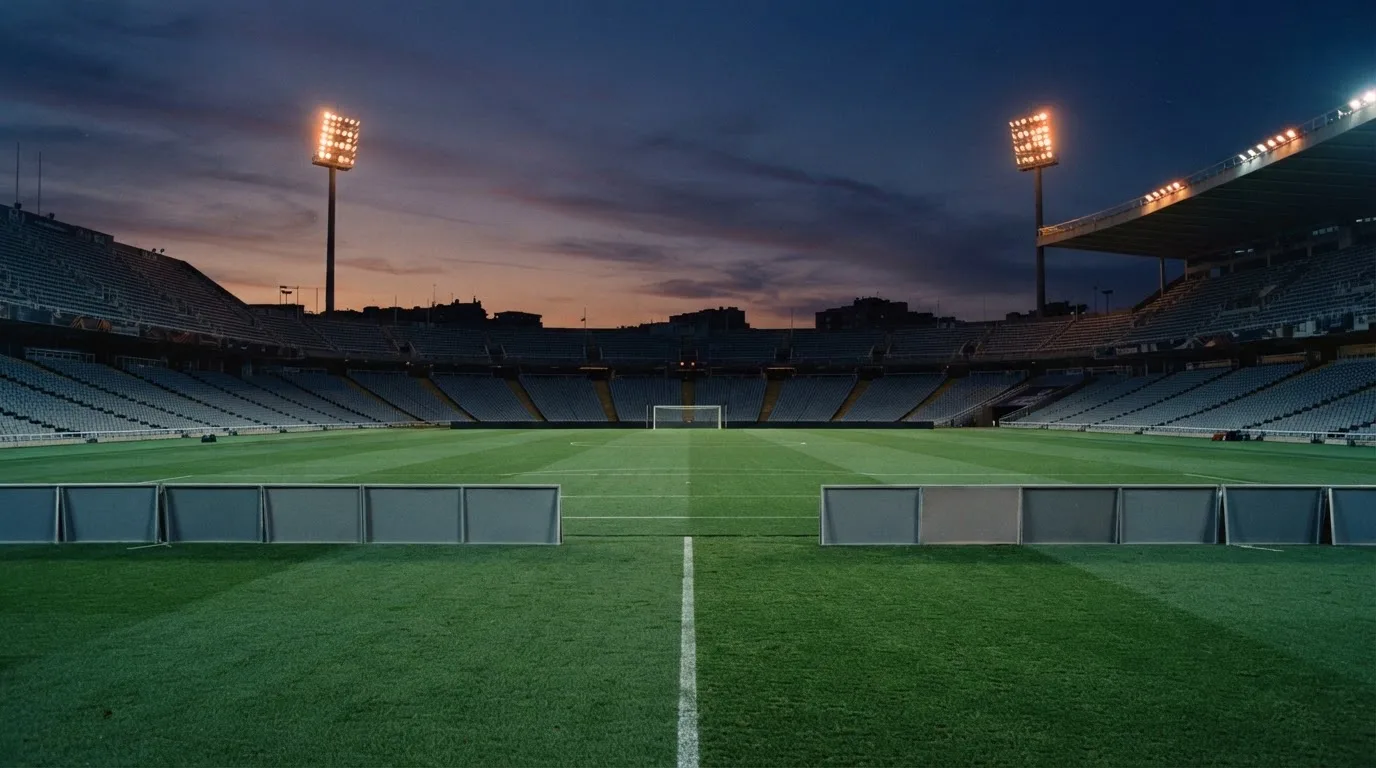An empty football stadium with floodlight masts at dusk