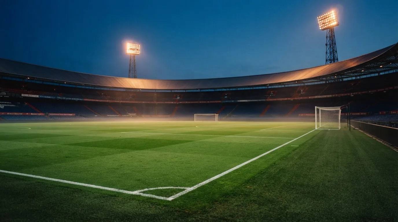 An empty football stadium with floodlight masts at dusk