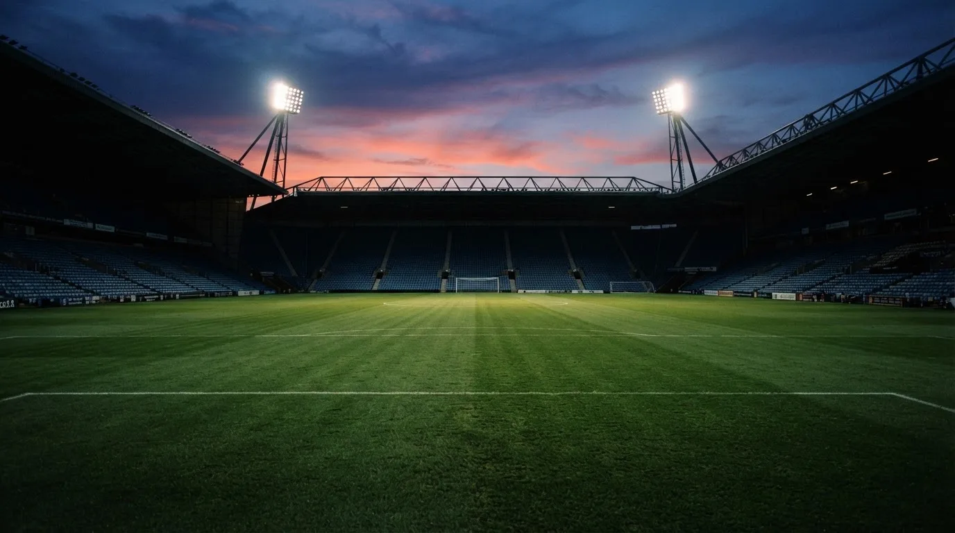 An empty football stadium with floodlight masts at dusk