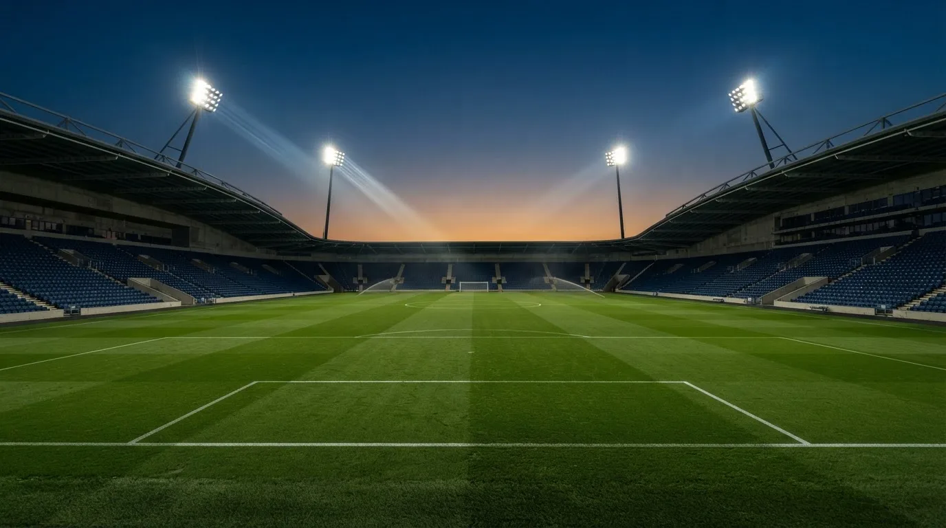 An empty football stadium with floodlight masts at dusk
