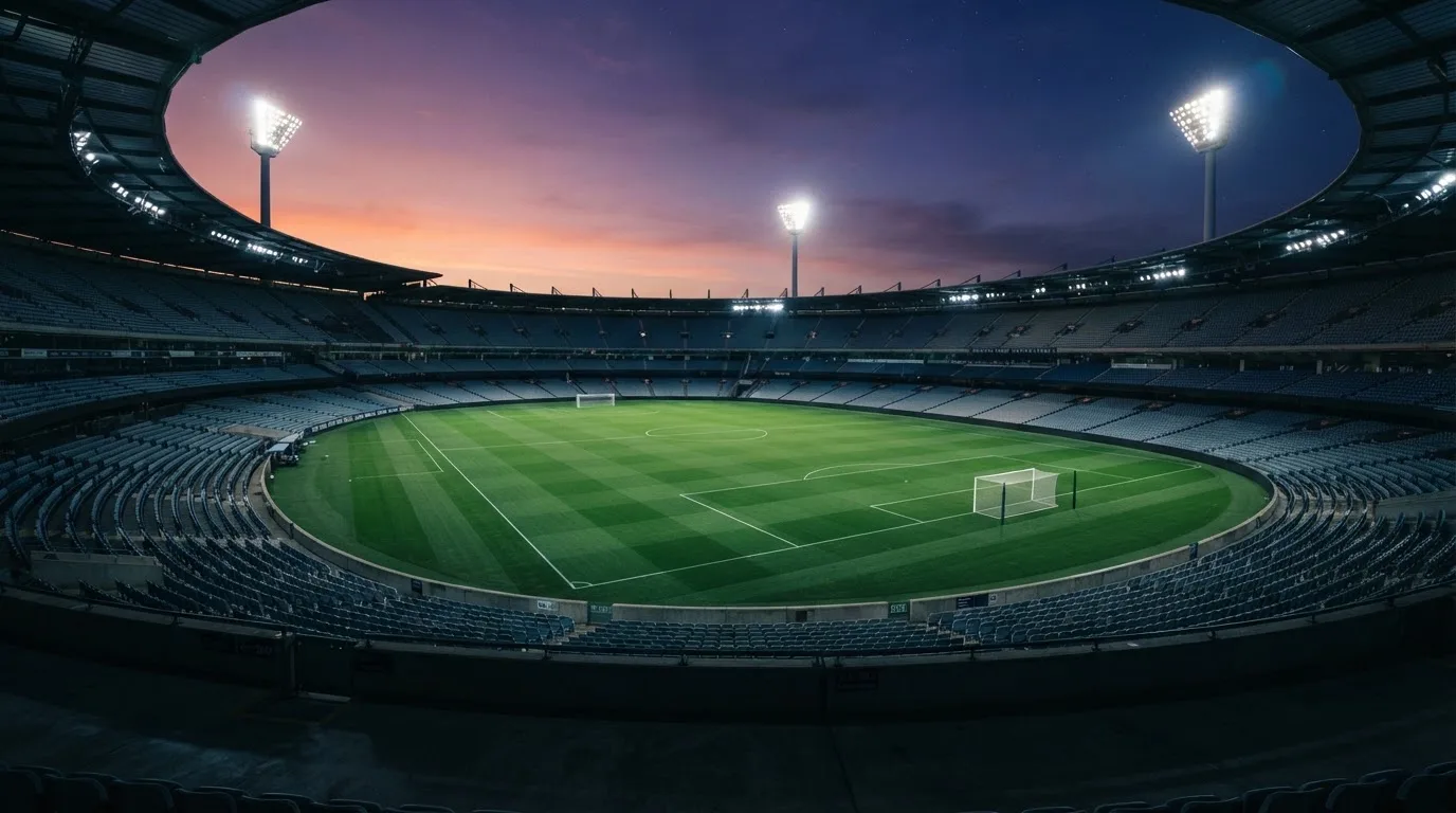 An empty football stadium with floodlight masts at dusk