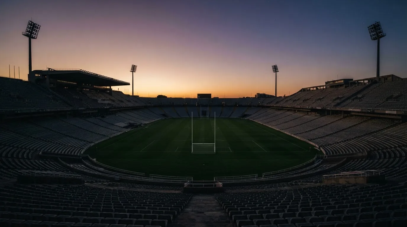 An empty football stadium with floodlight masts at dusk