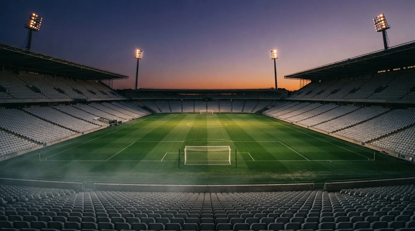 An empty football stadium with floodlight masts at dusk