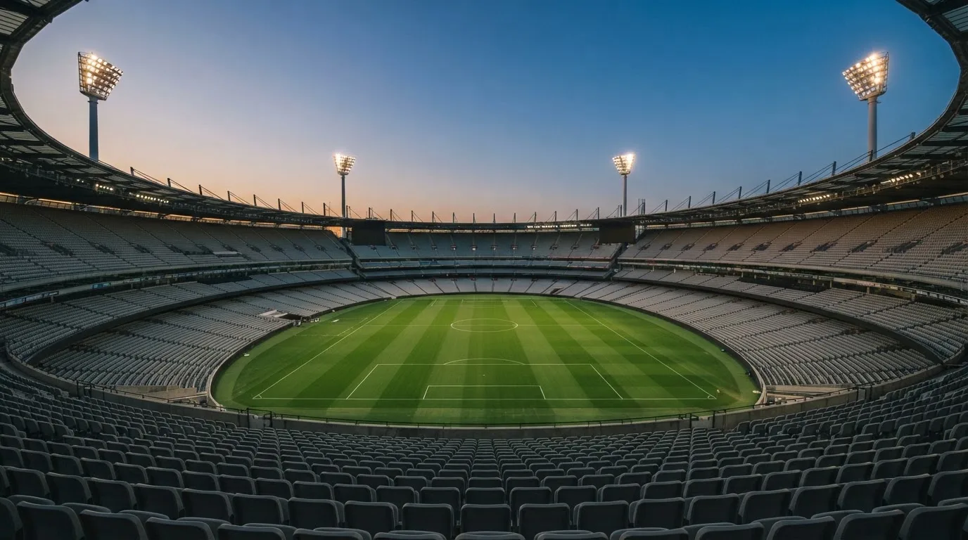 An empty football stadium with floodlight masts at dusk