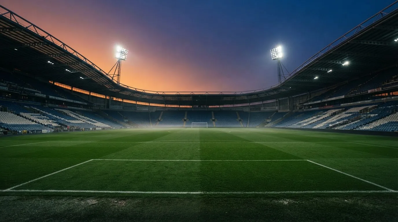 An empty football stadium with floodlight masts at dusk