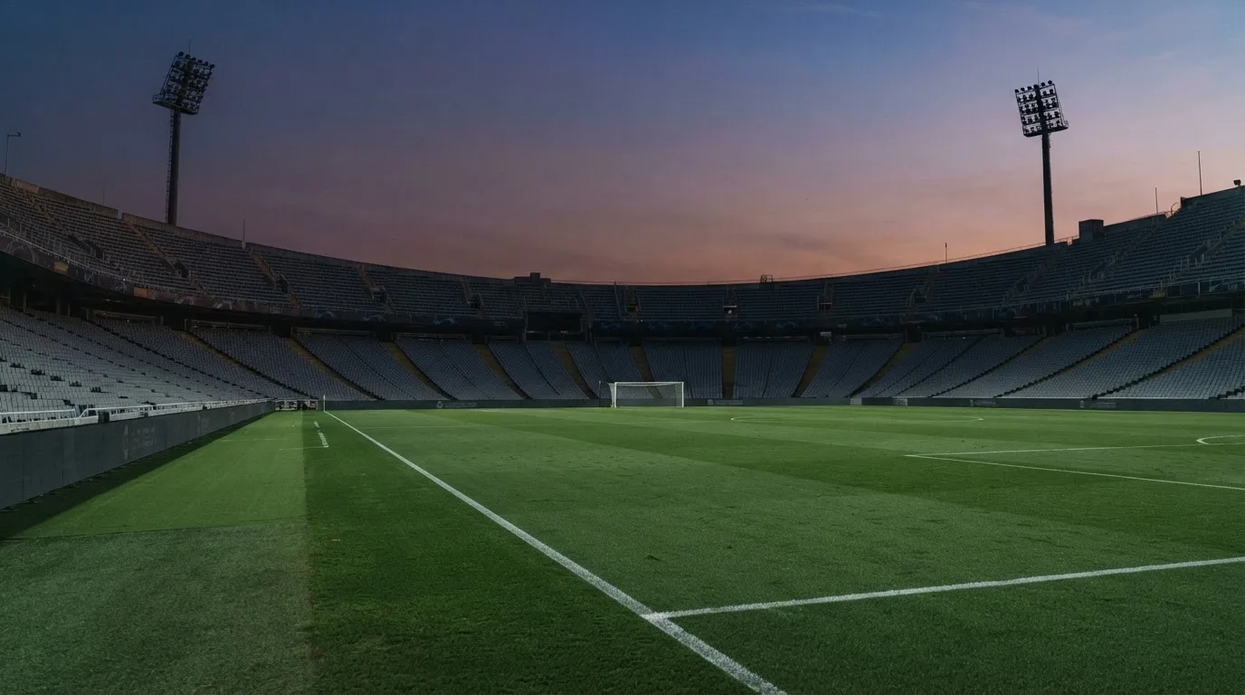 An empty football stadium with floodlight masts at dusk