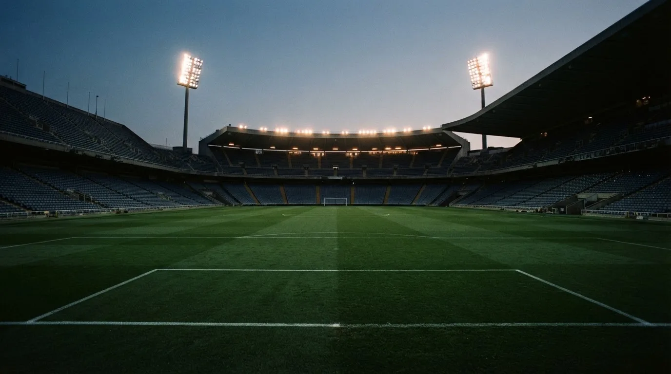 An empty football stadium with floodlight masts at dusk