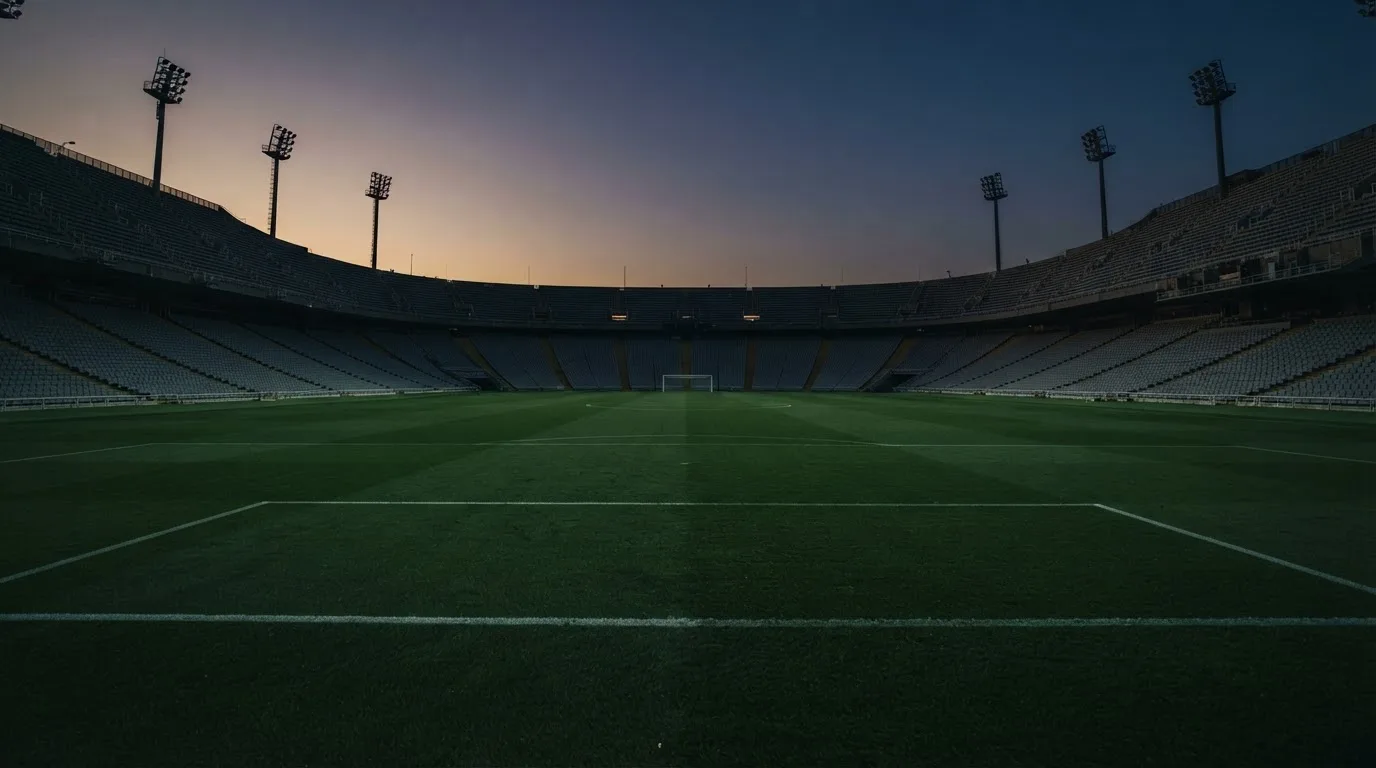 An empty football stadium with floodlight masts at dusk