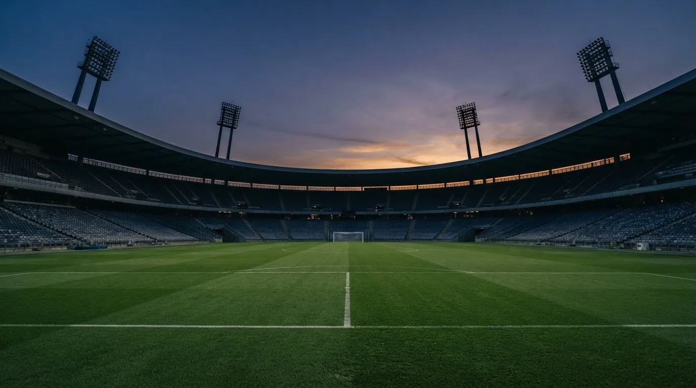 An empty football stadium with floodlight masts at dusk