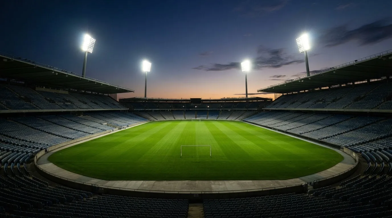 An empty football stadium with floodlight masts at dusk