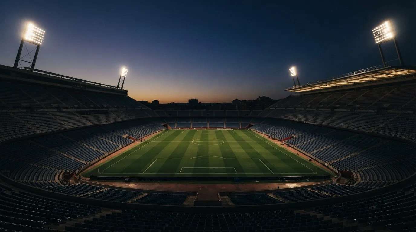 An empty football stadium with floodlight masts at dusk