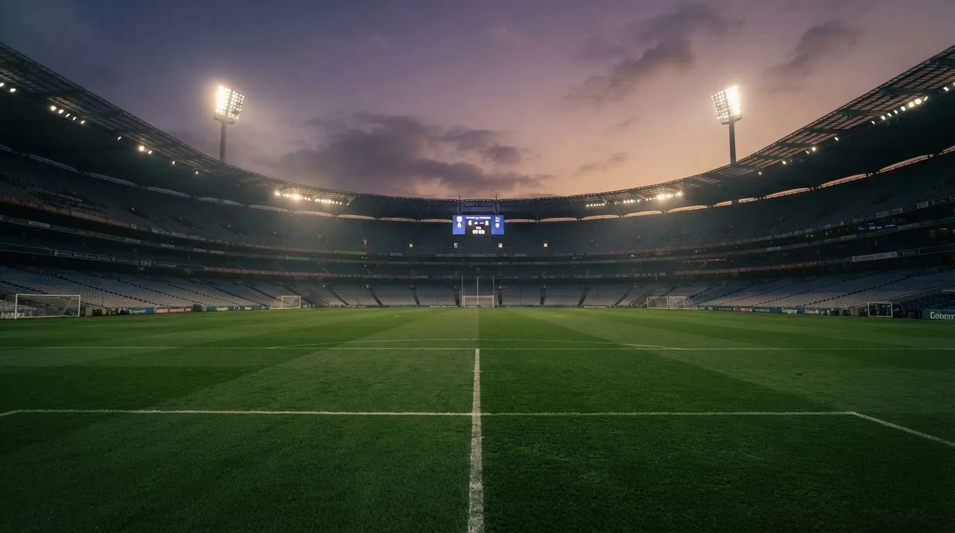 An empty football stadium with floodlight masts at dusk