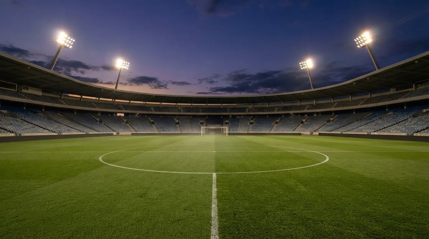 An empty football stadium with floodlight masts at dusk