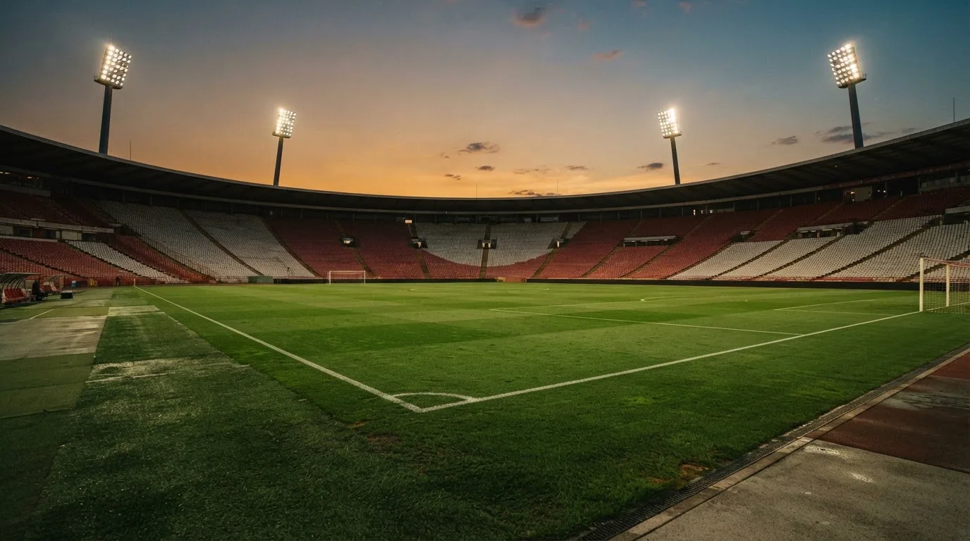 An empty football stadium with floodlight masts at dusk