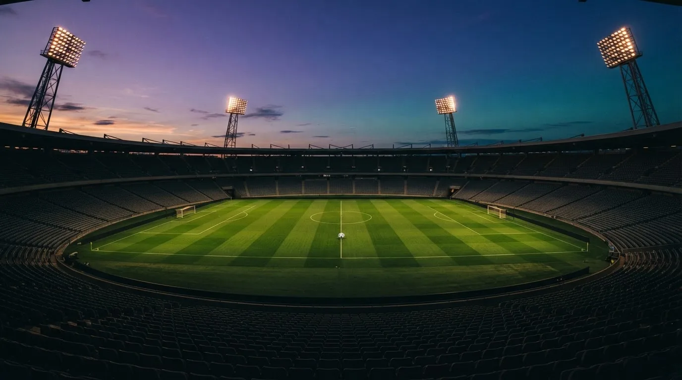 An empty football stadium with floodlight masts at dusk