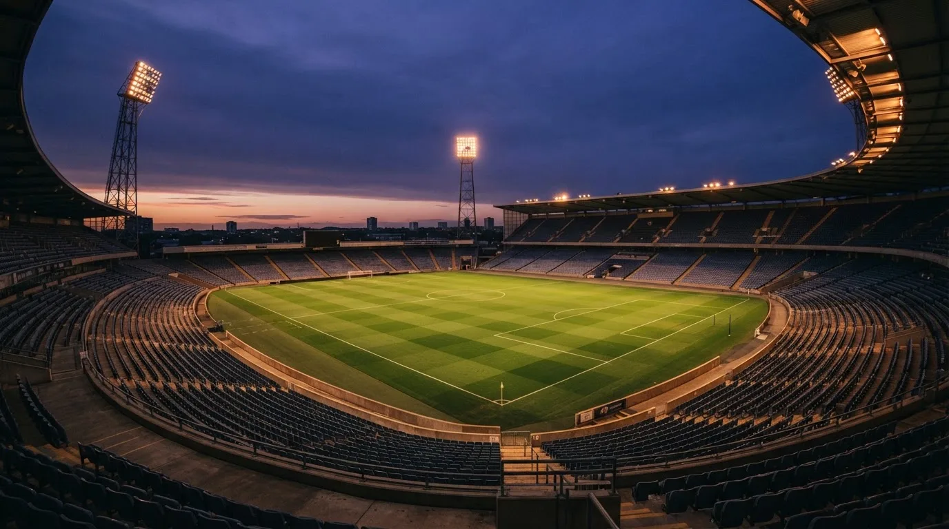 An empty football stadium with floodlight masts at dusk