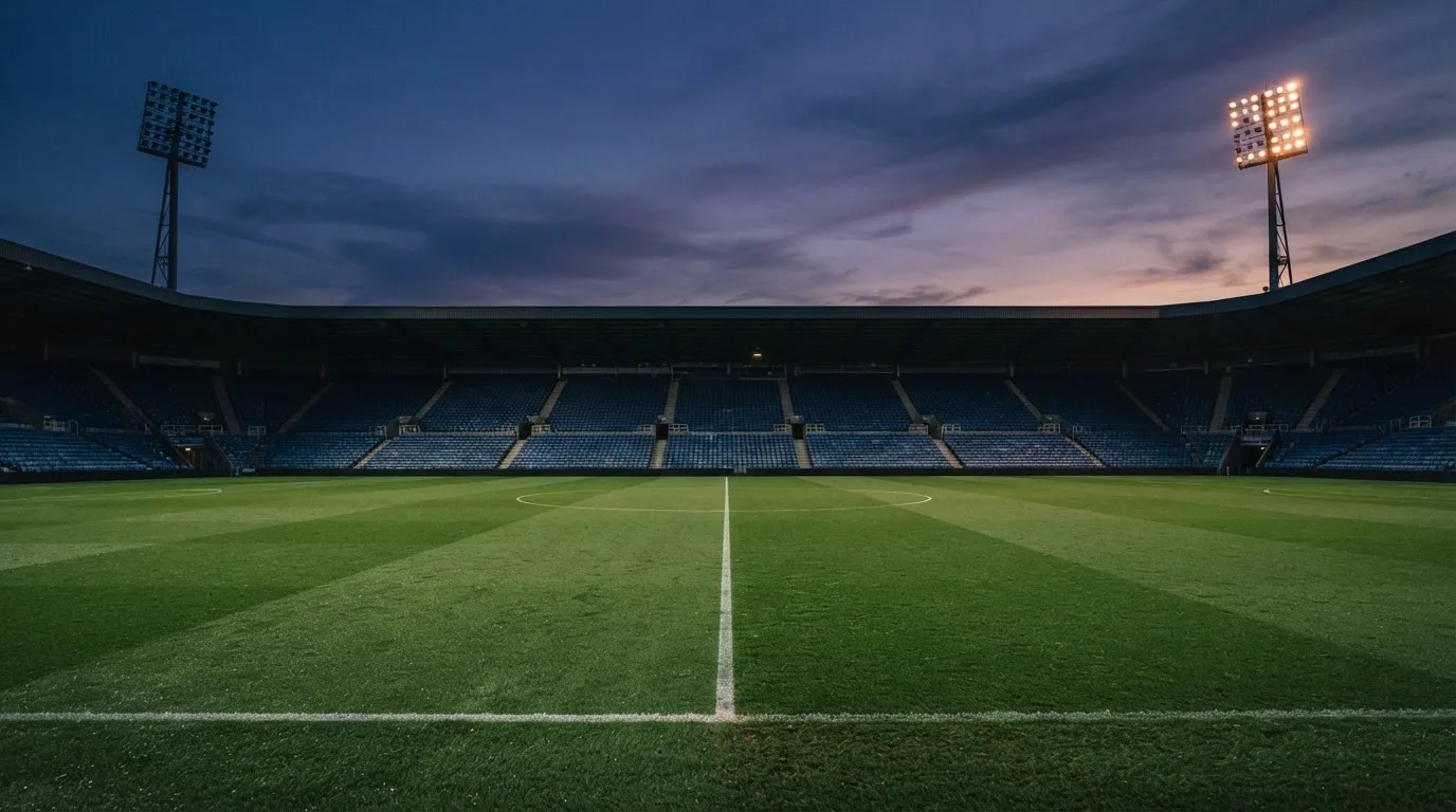 An empty football stadium with floodlight masts at dusk