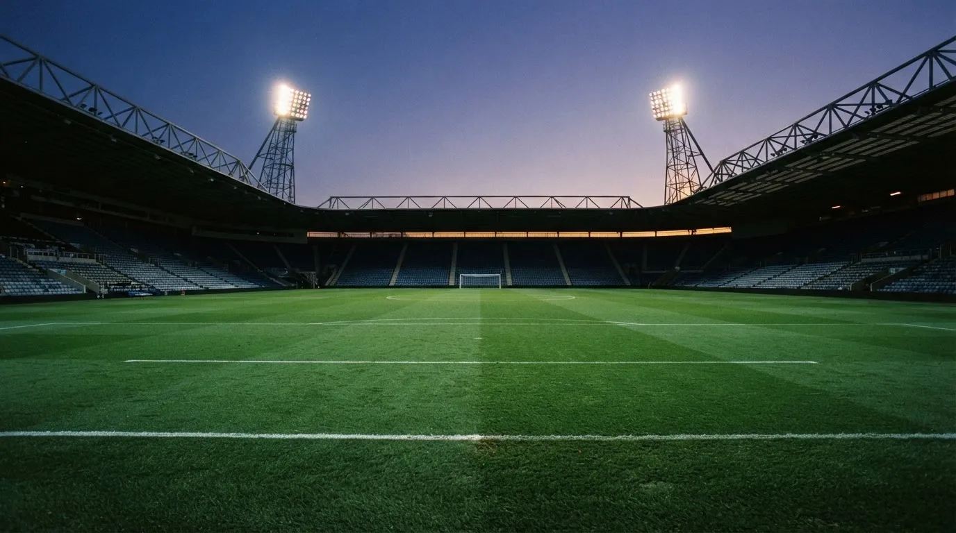 An empty football stadium with floodlight masts at dusk