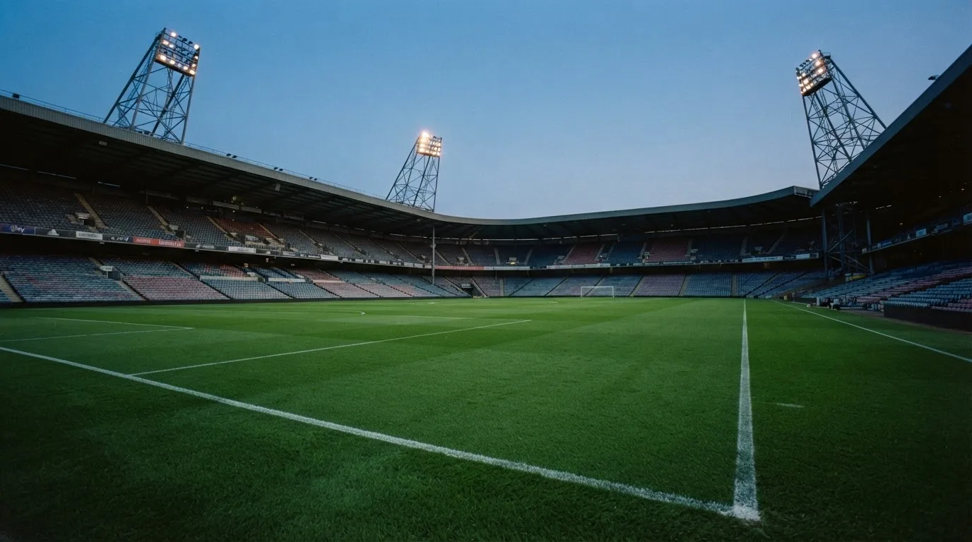 An empty football stadium with floodlight masts at dusk