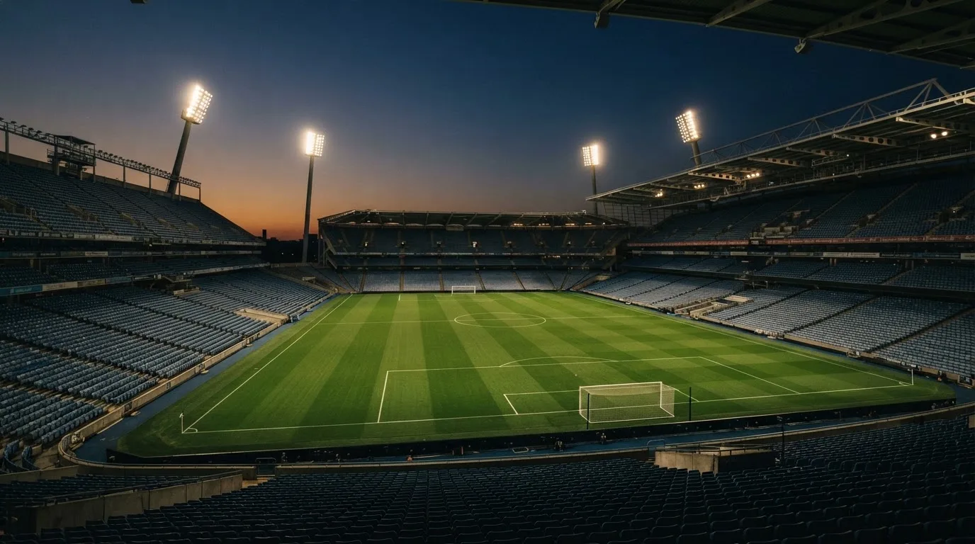 An empty football stadium with floodlight masts at dusk
