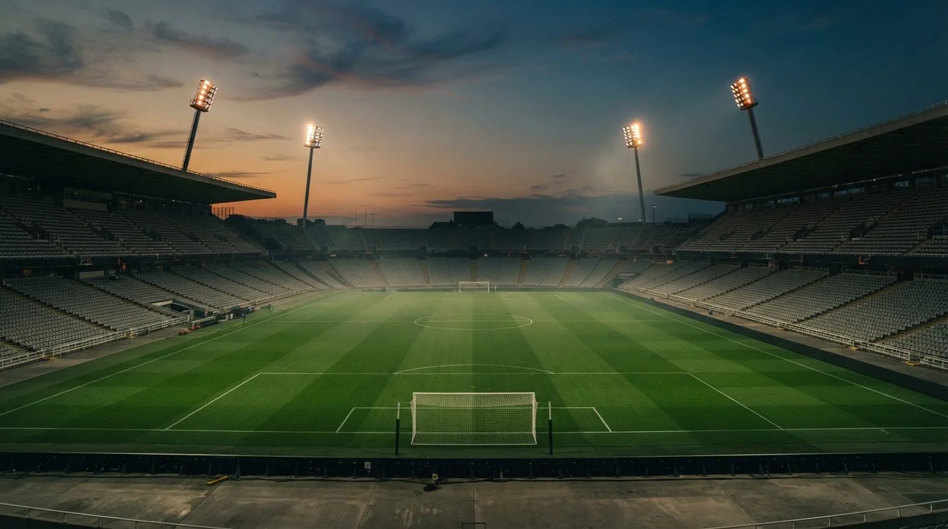 An empty football stadium with floodlight masts at dusk