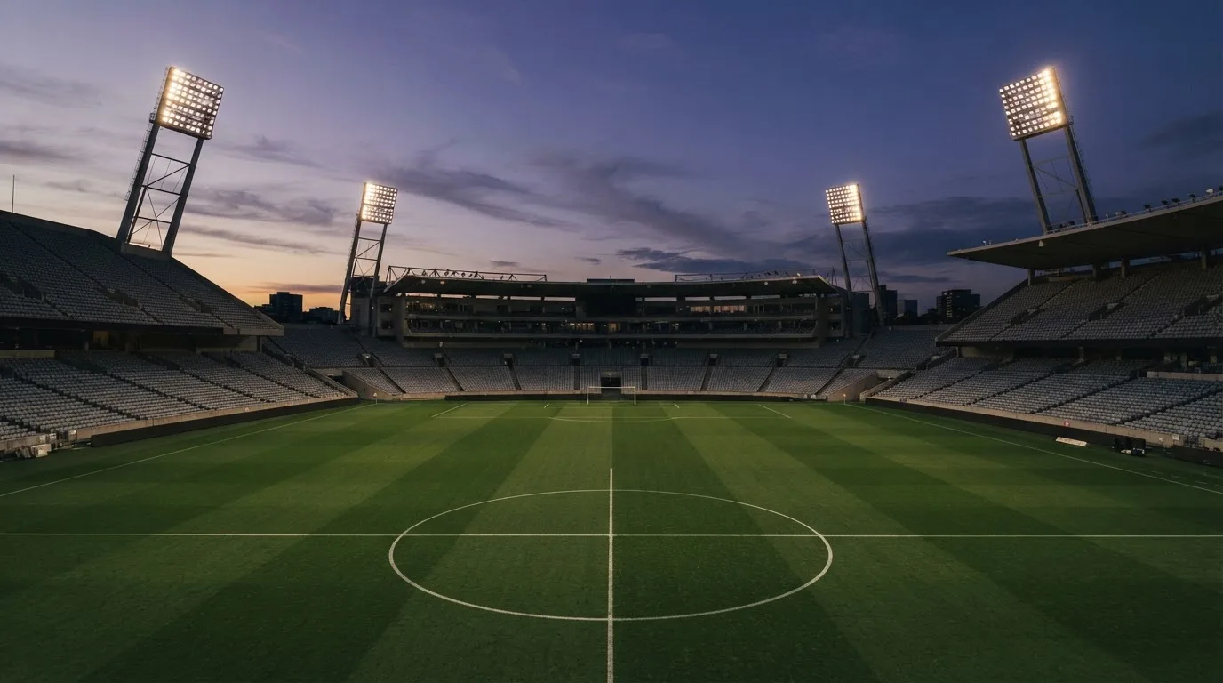An empty football stadium with floodlight masts at dusk