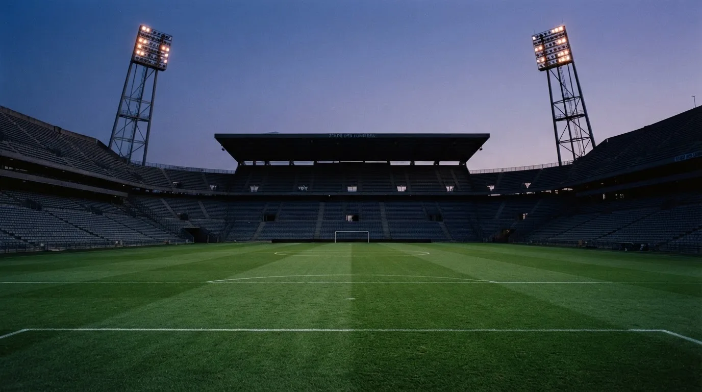 An empty football stadium with floodlight masts at dusk