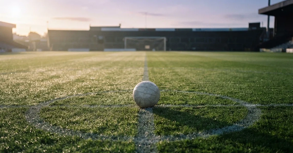A ball on the centre spot of a grass pitch in morning light