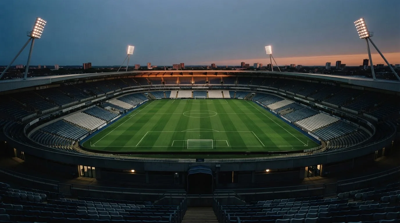 An empty football stadium with floodlight masts at dusk