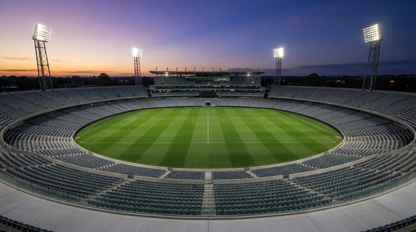 An empty football stadium with floodlight masts at dusk