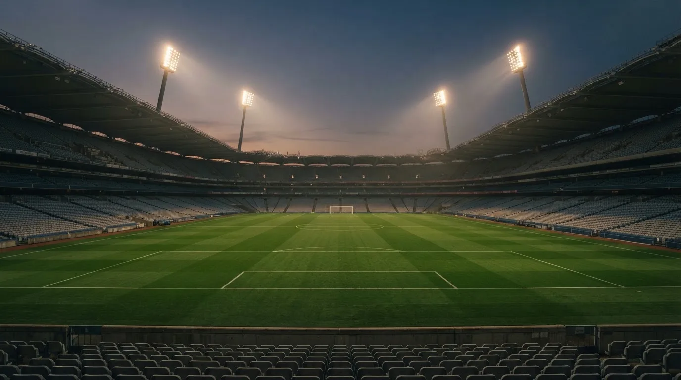 An empty football stadium with floodlight masts at dusk