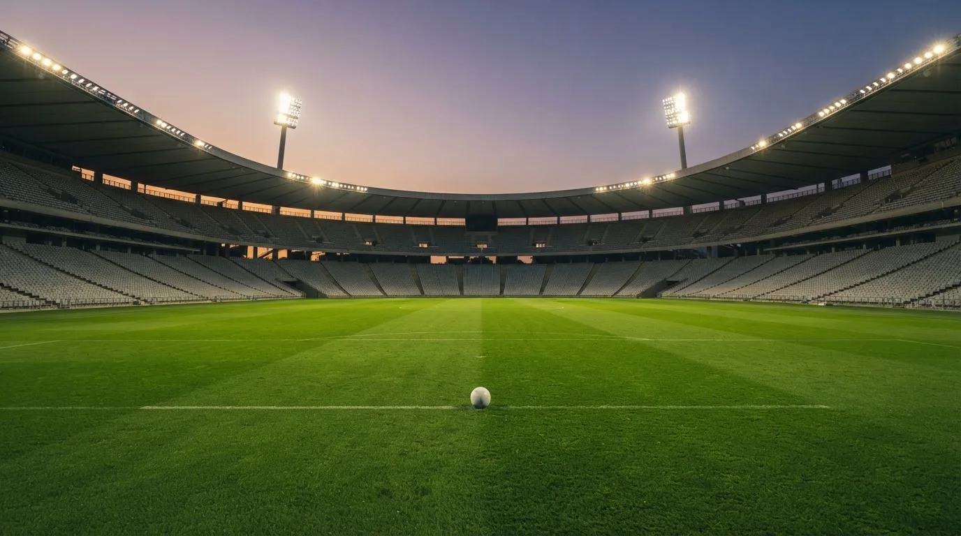 An empty football stadium with floodlight masts at dusk
