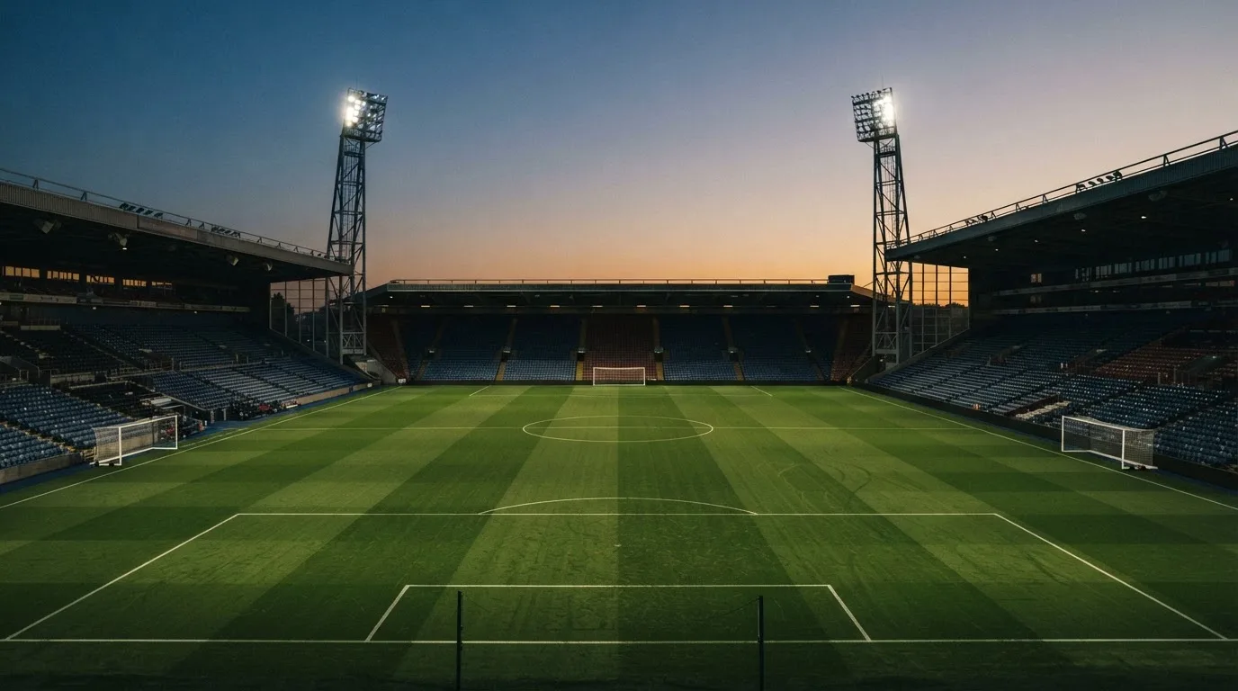 An empty football stadium with floodlight masts at dusk