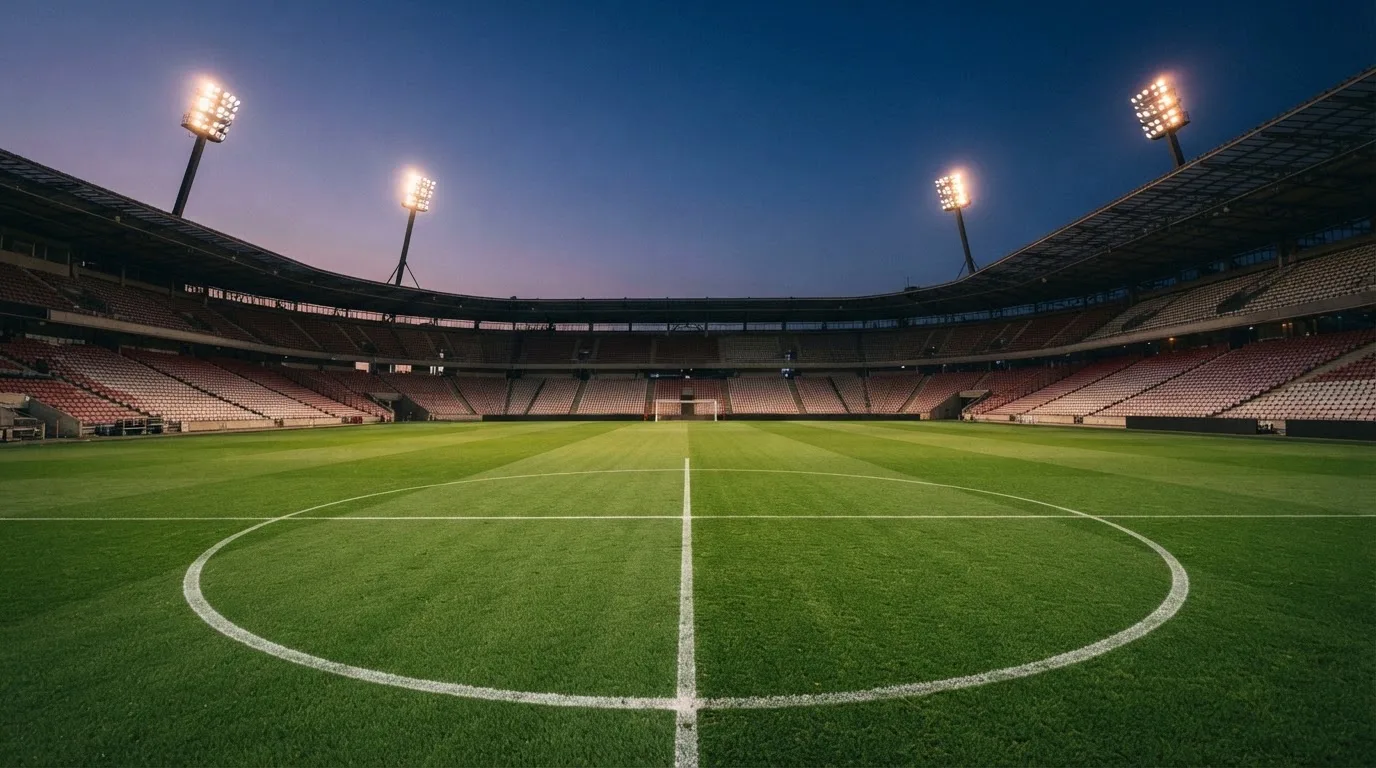 An empty football stadium with floodlight masts at dusk