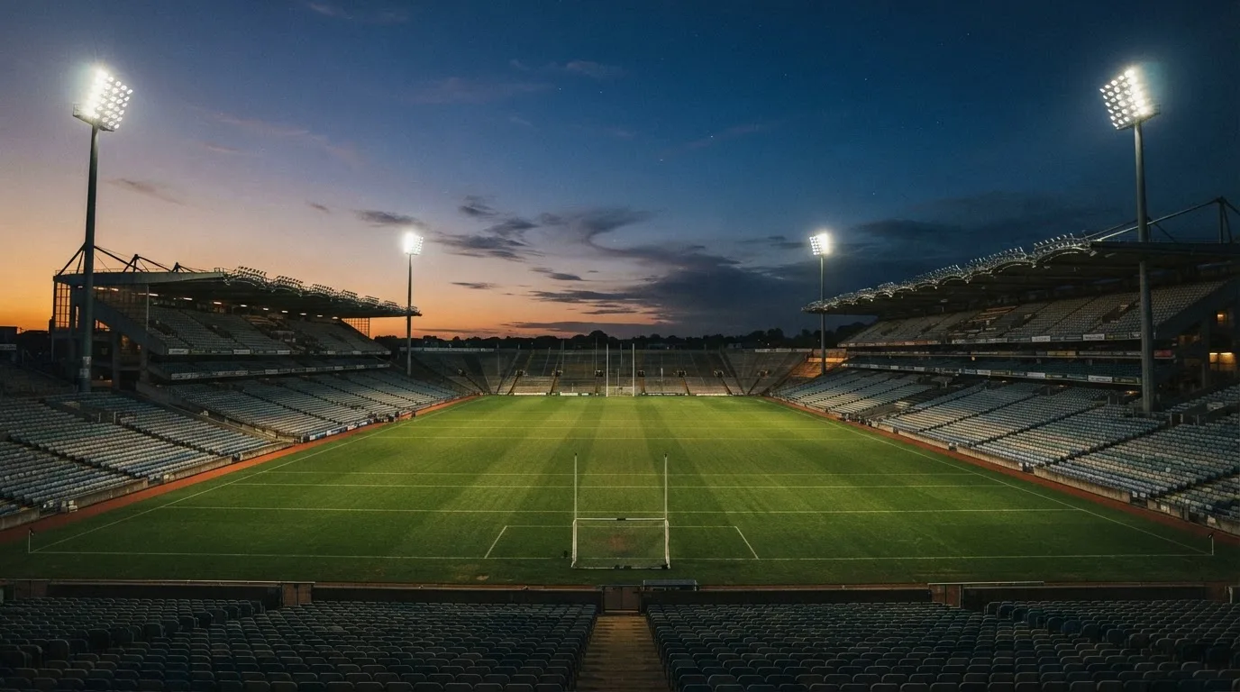 An empty football stadium with floodlight masts at dusk