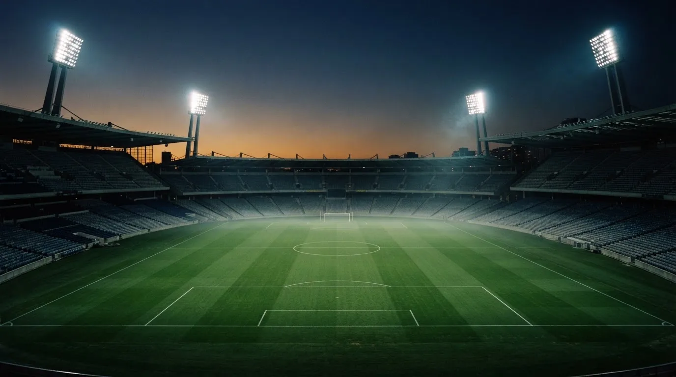 An empty football stadium with floodlight masts at dusk