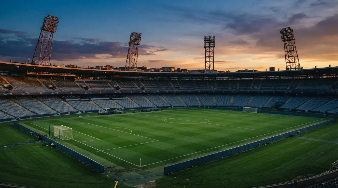 An empty football stadium with floodlight masts at dusk