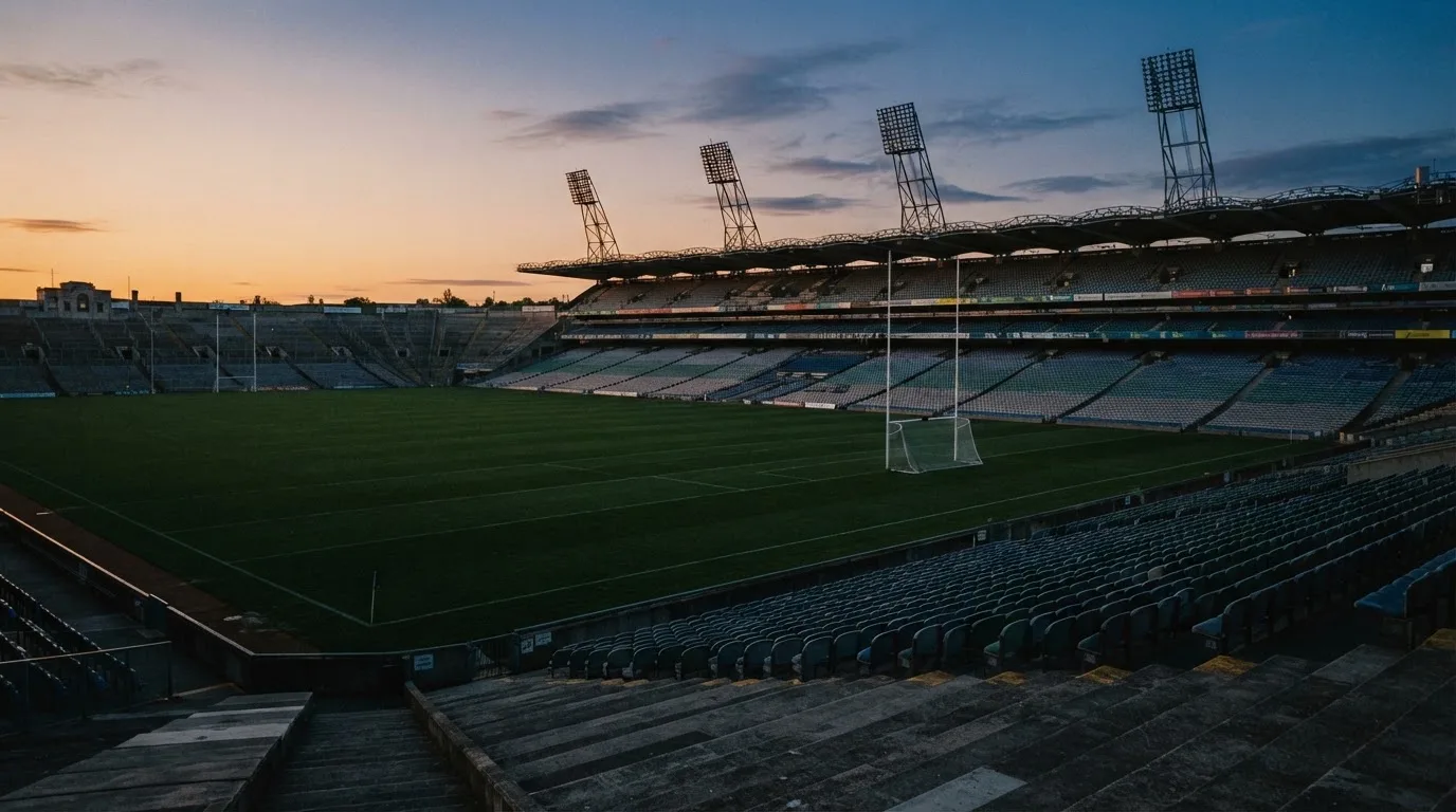 An empty football stadium with floodlight masts at dusk