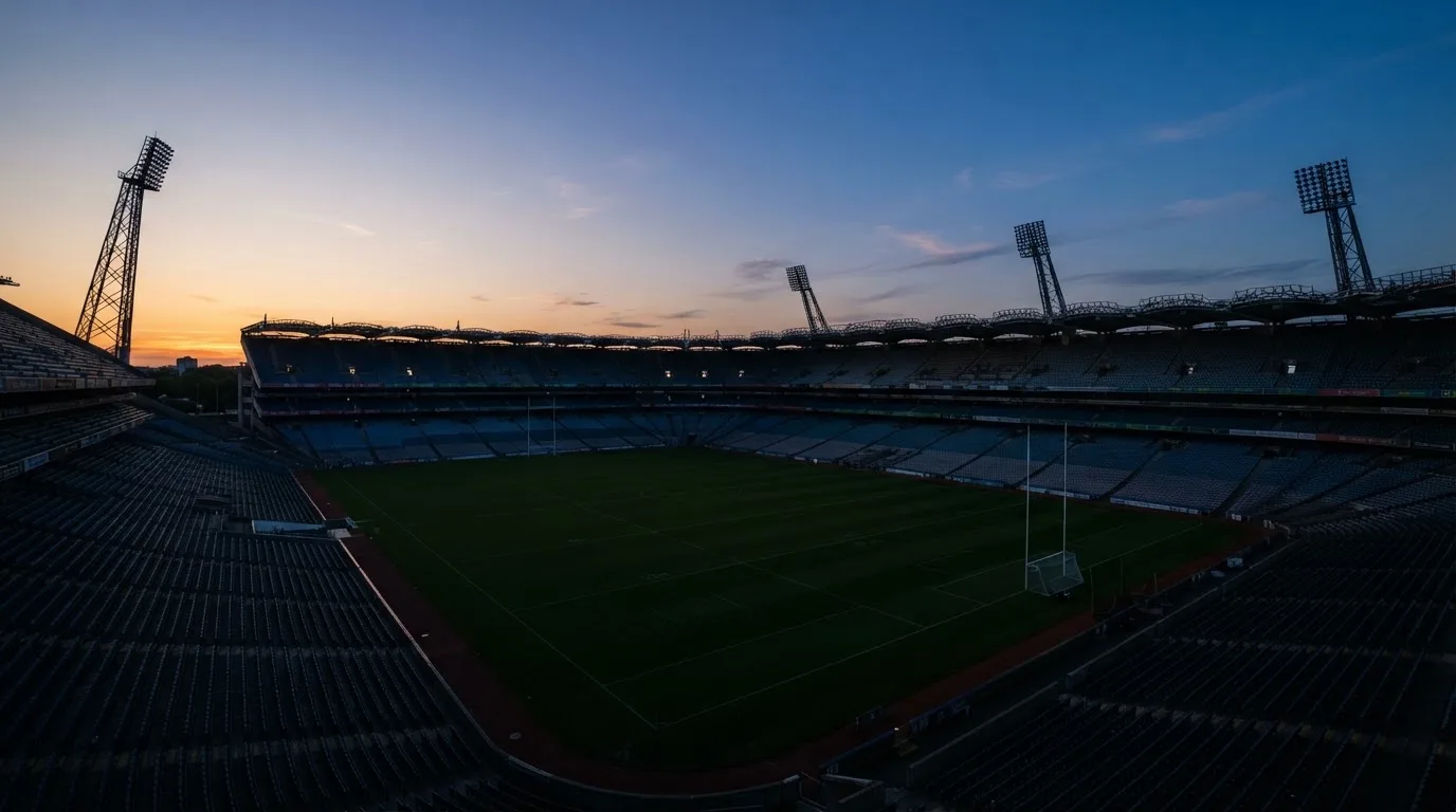 An empty football stadium with floodlight masts at dusk