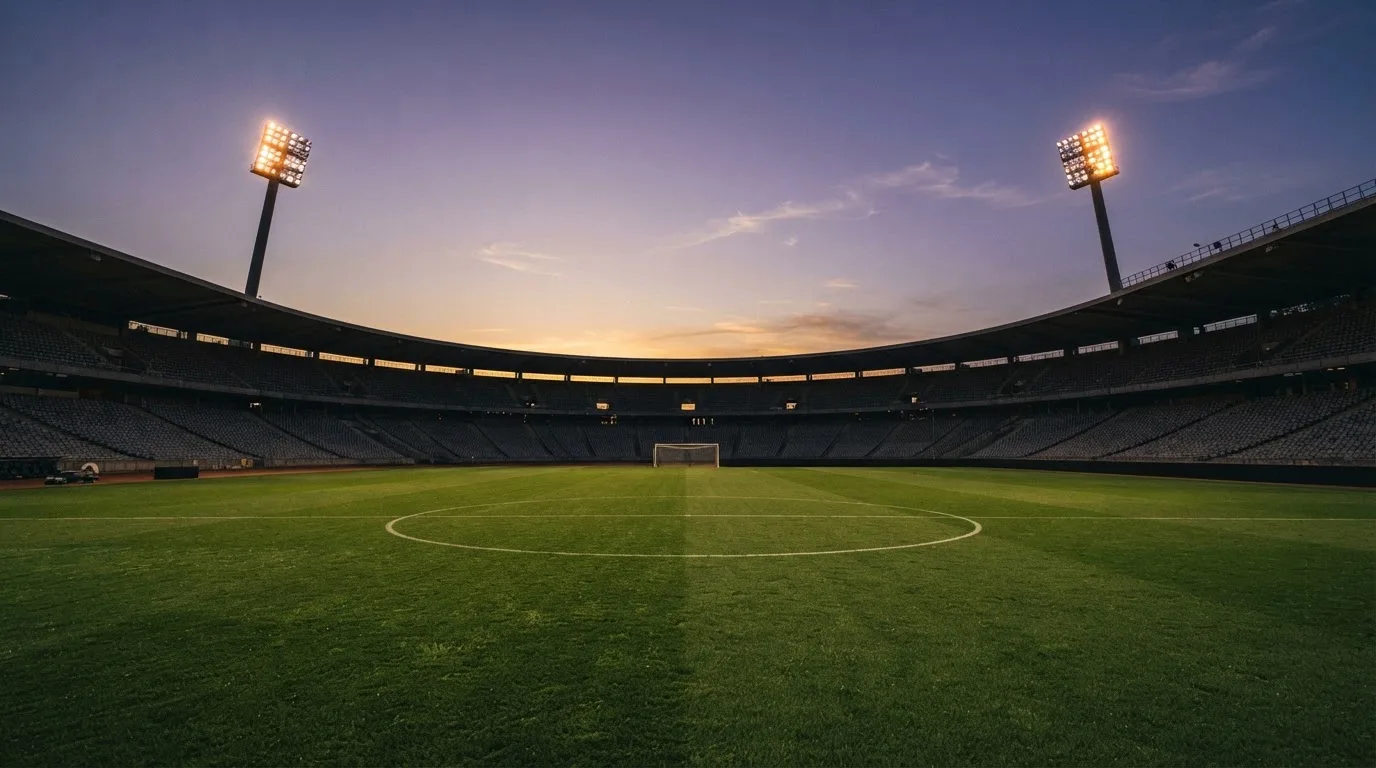 An empty football stadium with floodlight masts at dusk