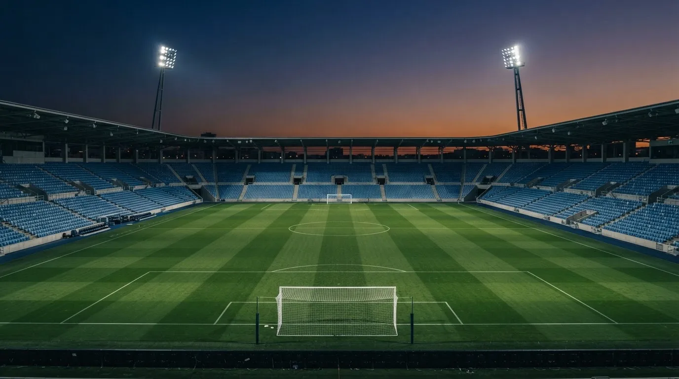 An empty football stadium with floodlight masts at dusk