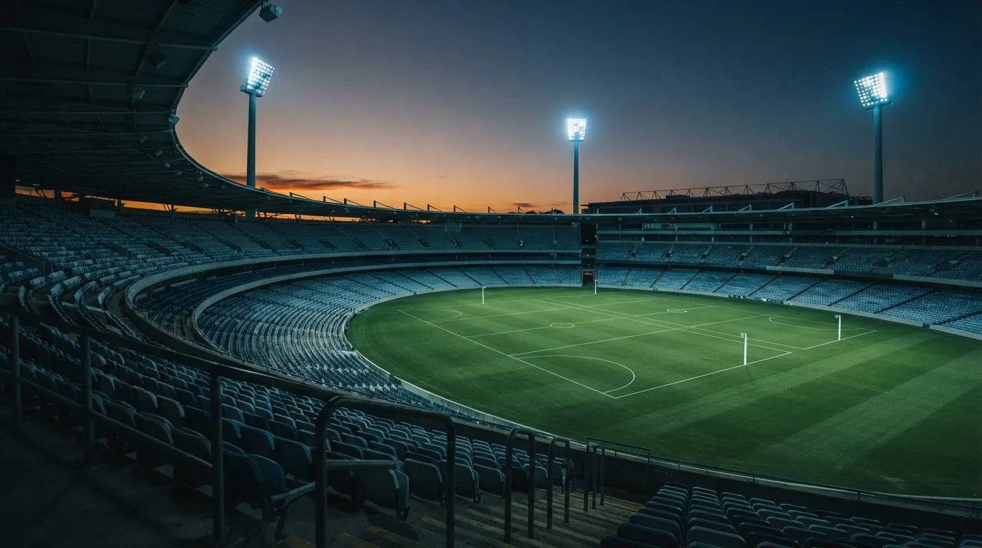 An empty football stadium with floodlight masts at dusk