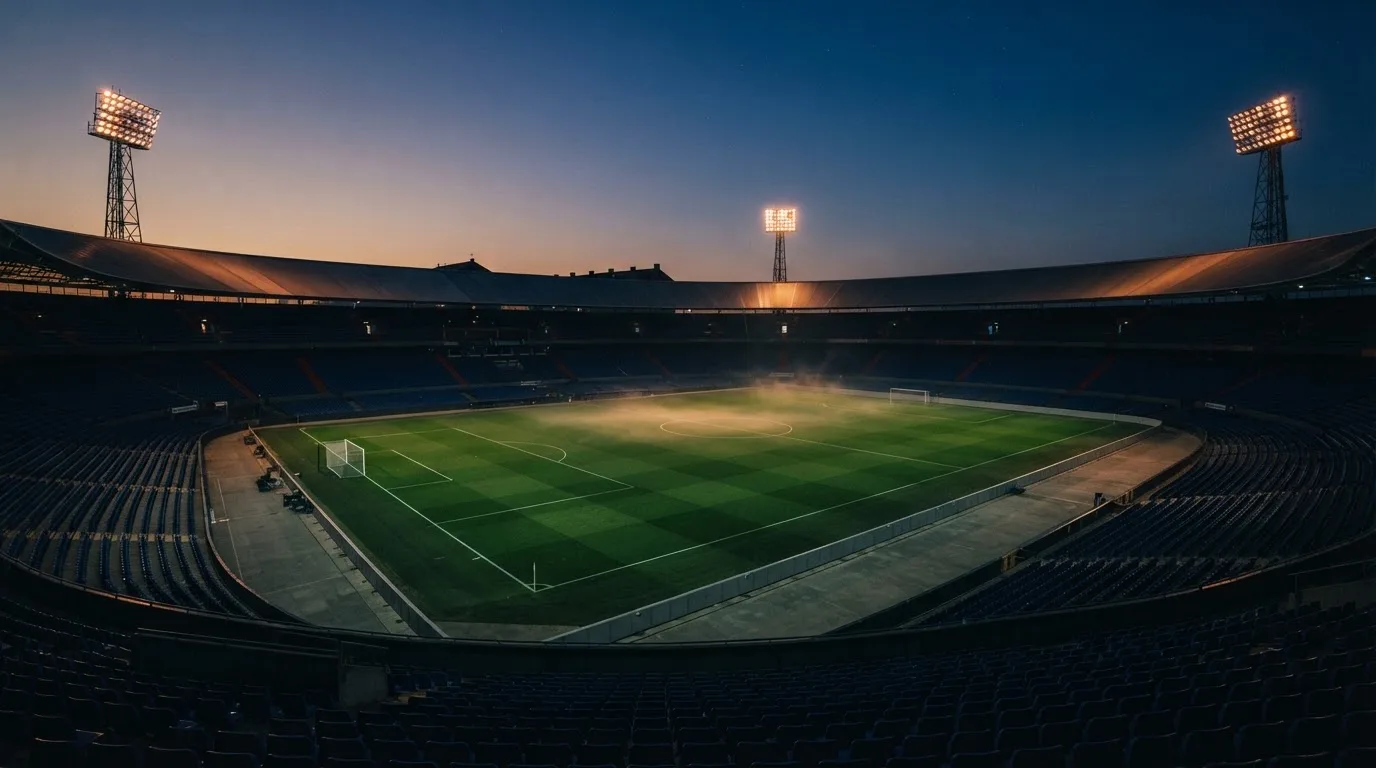 An empty football stadium with floodlight masts at dusk