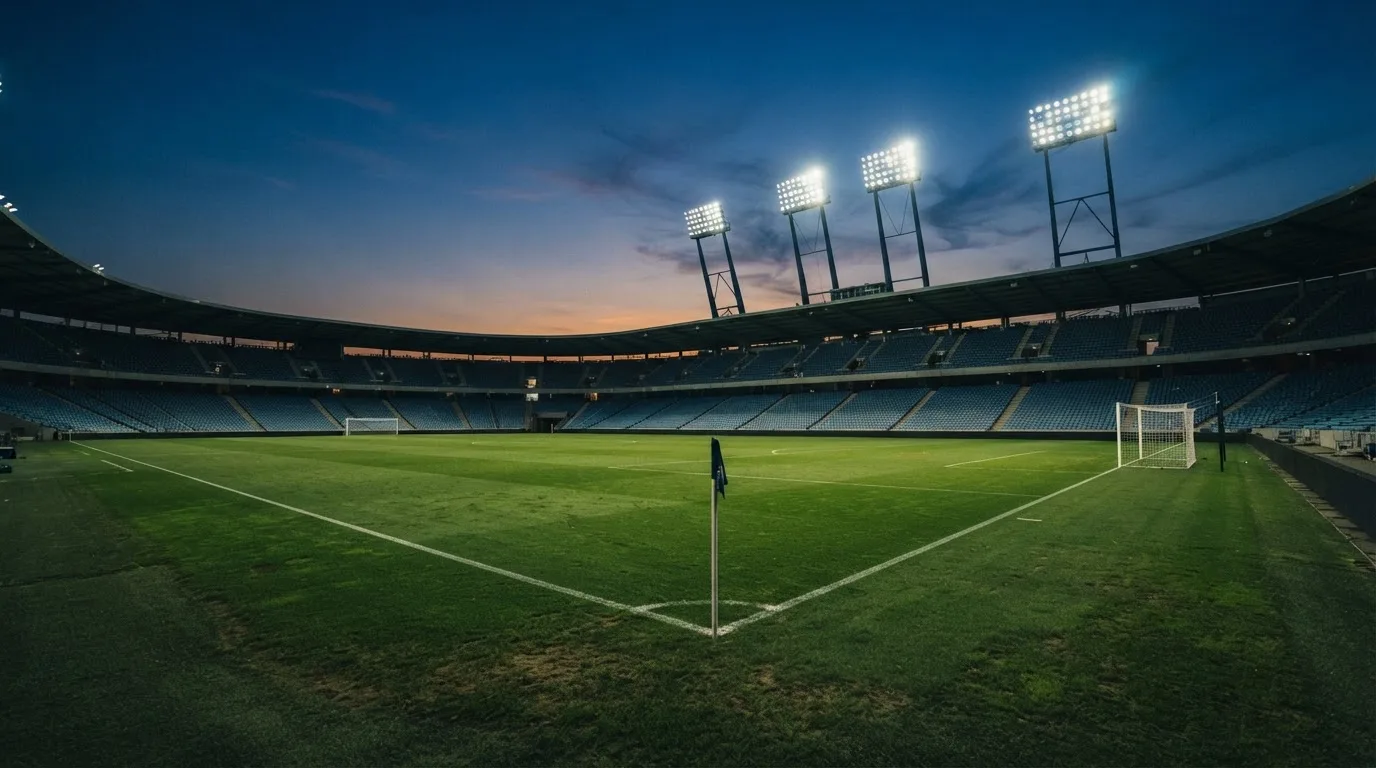 An empty football stadium with floodlight masts at dusk