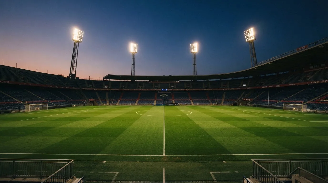 An empty football stadium with floodlight masts at dusk