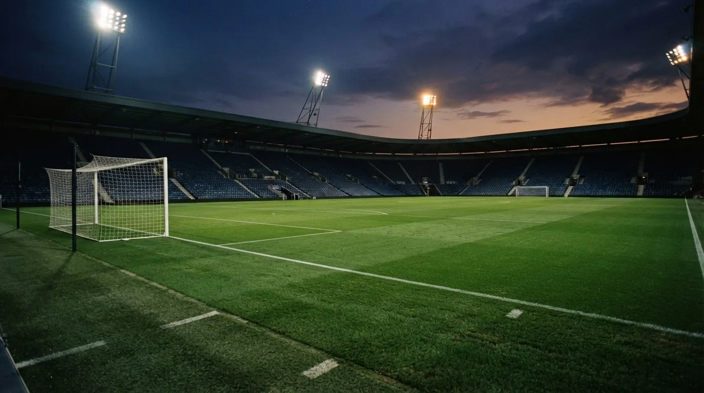 An empty football stadium with floodlight masts at dusk