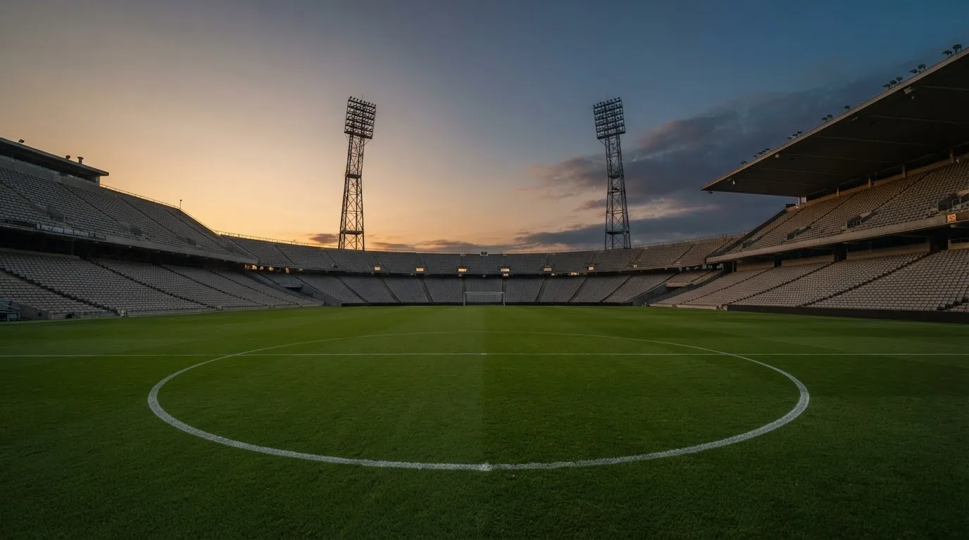 An empty football stadium with floodlight masts at dusk