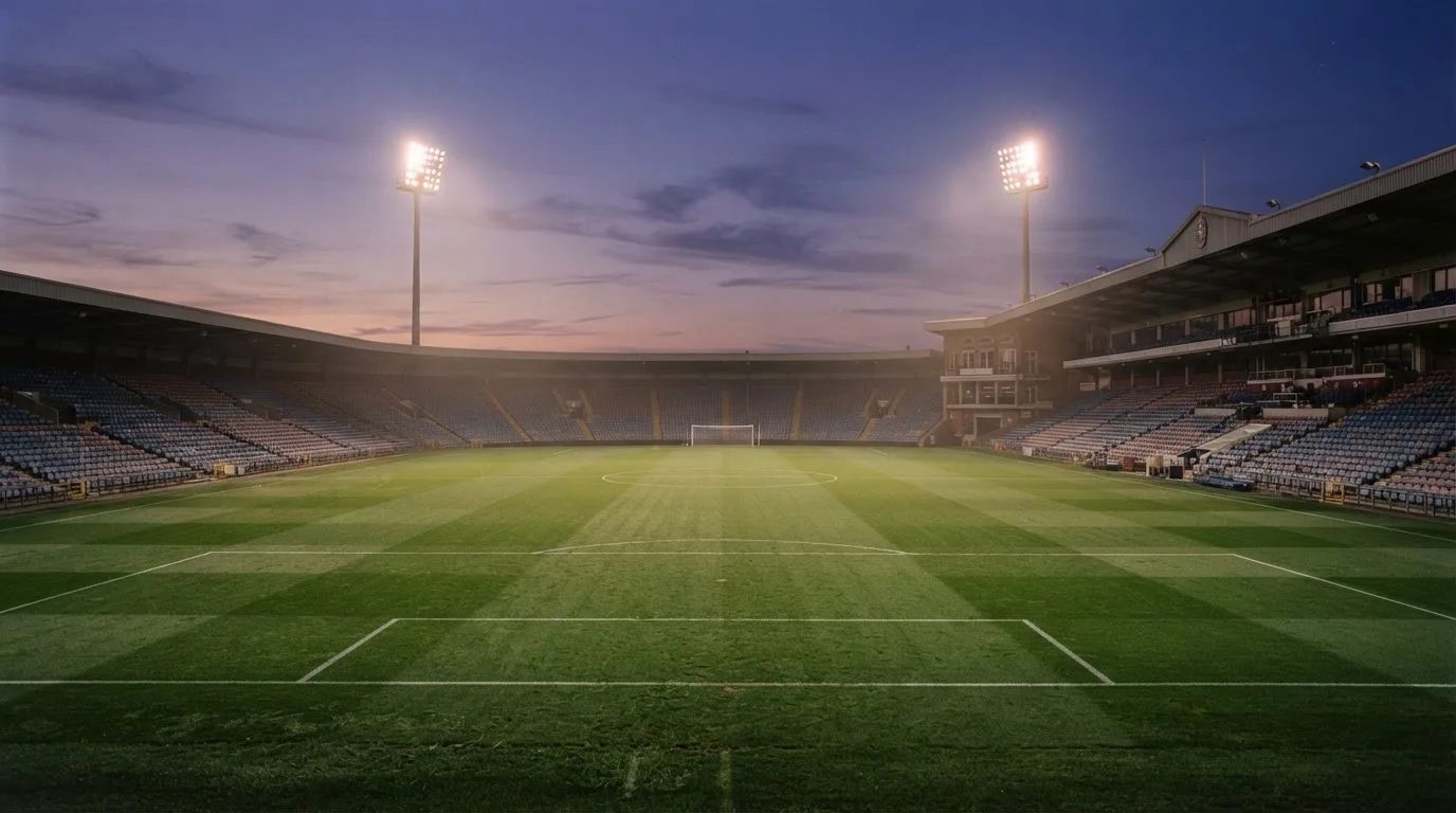 An empty football stadium with floodlight masts at dusk