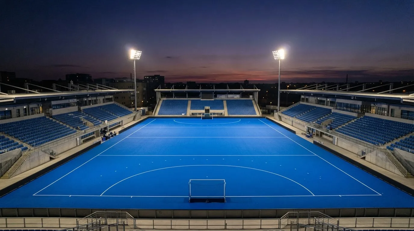 An empty football stadium with floodlight masts at dusk