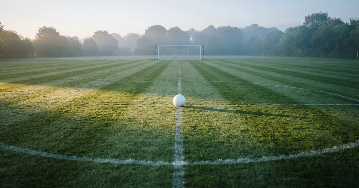 A ball on the centre spot of a grass pitch in morning light